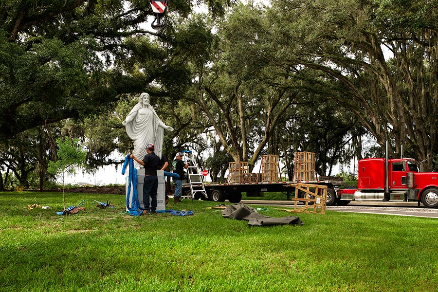 Nan Nguyen removes the slings after a crane places the larger-than-life granite statue of Jesus Christ in place at Resurrection Cemetery, Hillsborough County, Fla.